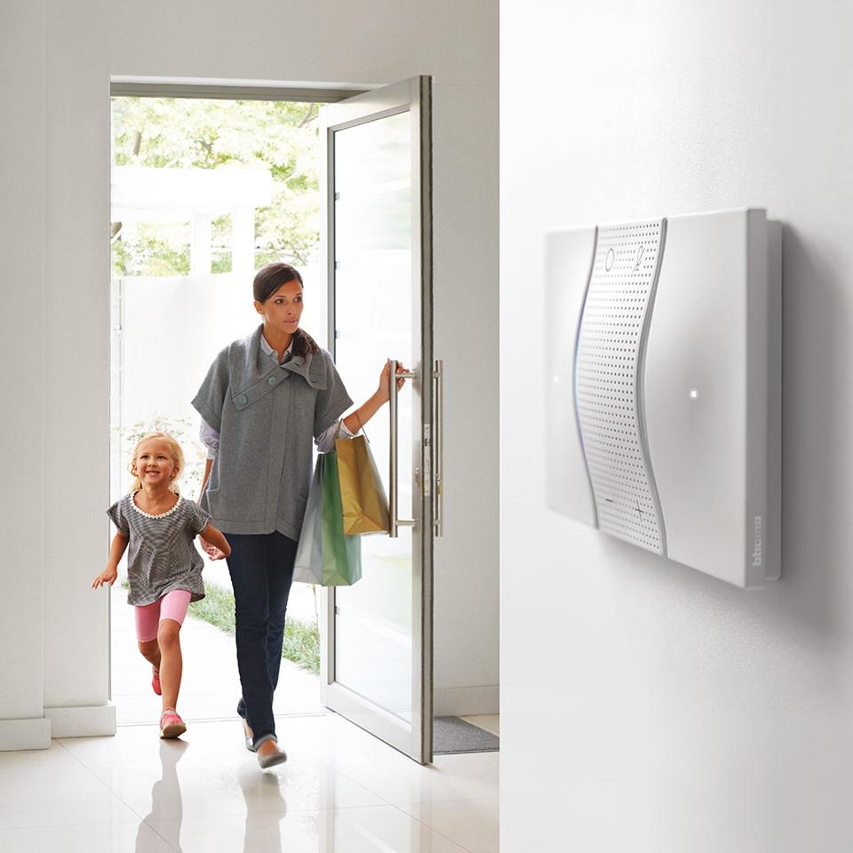 Mamma e figlia entrano in casa, in primo piano comando vocale domotico con Alexa integrato