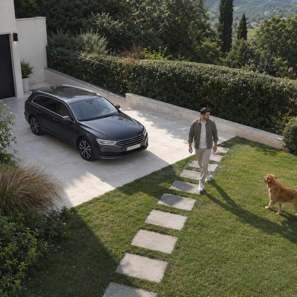 Un uomo attraversa il giardino di una casa moderna, tra un’auto parcheggiata e un Golden Retriever