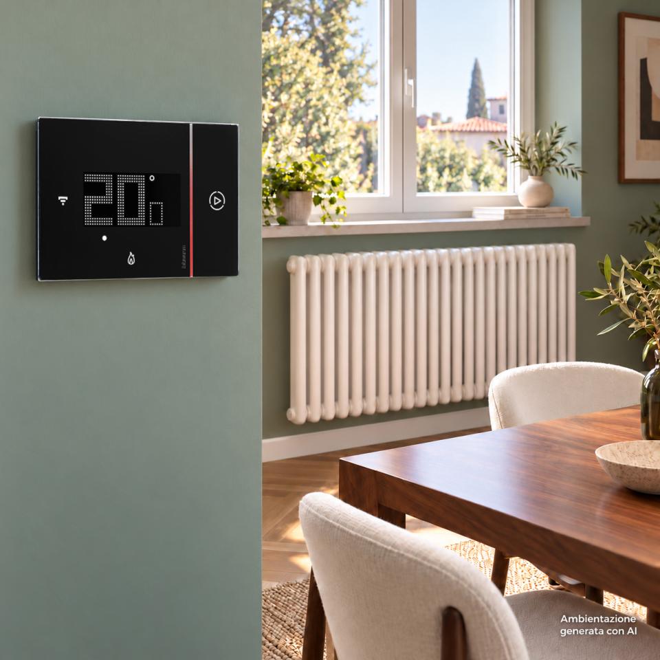 Termostato Smarther2 nero, installato a parete in un soggiorno con calorifero